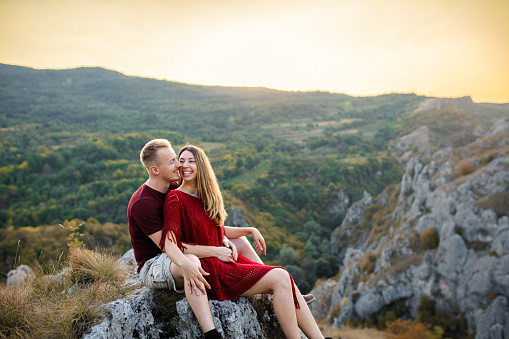 Young couple resting and admiring the view from the mountain