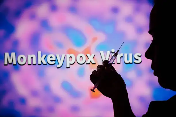 A person holding a medical syringe with the word Monkeypox in the background. It is a viral disease that occurs mainly in central and western Africa. It's called monkeypox.