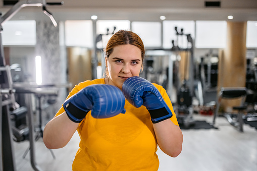 Portrait of a young plus size female boxer in the gym.