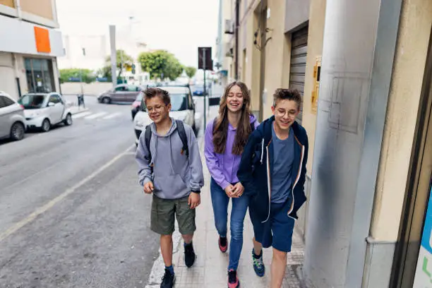 Photo of Cool teenagers walking to school on city street