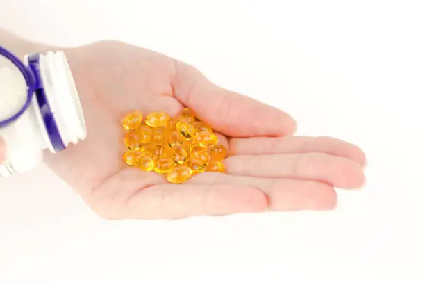 Yellow pills in a female hand. Vitamin Omega-3 in a female hand in capsules. Yellow fish oil capsules