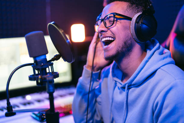 istock Young male singer in recording studio performing in neon lights 1398826392