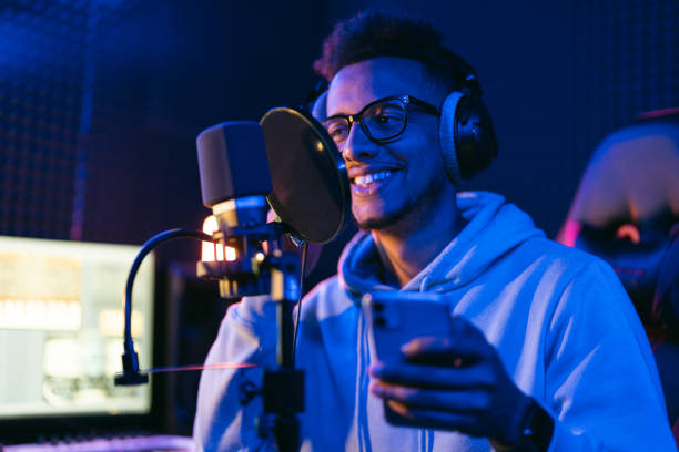 Young male singer in recording studio performing in neon lights use smartphone stock photo