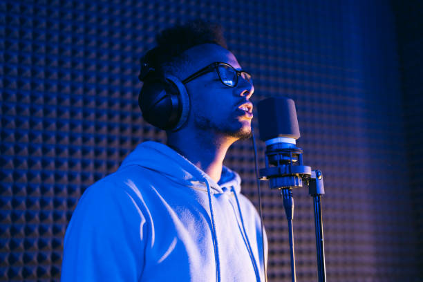 istock Young male singer in recording studio performing in neon lights 1398826554
