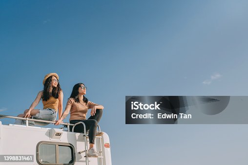 istock Asian Chinese Lesbian couple enjoying scenic view on top of campervan outdoor road trip during weekend morning 1398831461