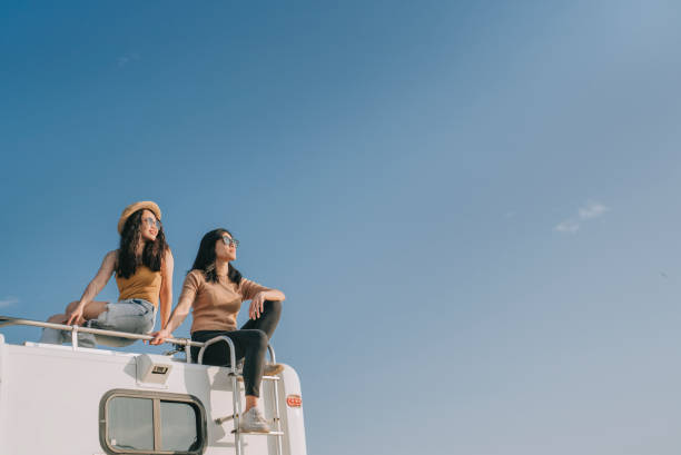 casal lésbico chinês asiático desfrutando vista cênica em cima de campervan viagem ao ar livre durante a manhã de fim de semana - travel trailer - fotografias e filmes do acervo