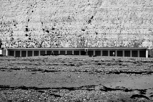 Rottingdean beach is set on the comparatively quiet stretch of coast between Brighton and Newhaven. This reasonably-sized beach is your typical Sussex affair, with a series of groynes and breakwaters to keep the pebbles place.\nAs the tide goes out the pebbles give way to an area of flat sand , but also some rockpools.\n\nThe beach is backed by a promenade, which forms part of Undercliff Walk, stretching from Brighton Marina to Saltdean. As the name suggests the path sits below the tall white chalk cliffs that are iconic along this coast.\n\nRottingdean has basic facilities including a small cafe and a seasonal lifeguard service. There are a few beach huts at the foot of the cliffs along with a basketball court.