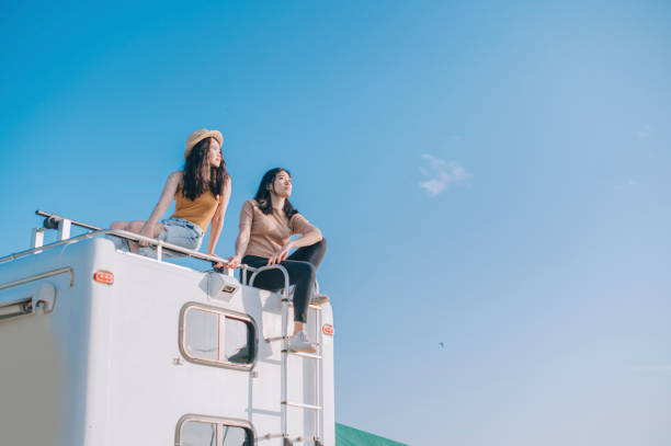 Asian Chinese Lesbian couple enjoying scenic view on top of campervan outdoor road trip during weekend morning Asian Chinese Lesbian couple enjoying scenic view on top of campervan outdoor road trip during weekend morning rv travel stock pictures, royalty-free photos & images