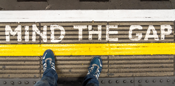 London, UK - Looking down to the words 'Mind The Gap', painted on the platform at a London Underground station.