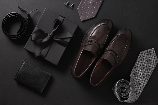Set of classic mens accessories - shoes, belt , wallet and gift on black background. Top view. Flat lay. Concept mens design and Fashion. Father's Day.