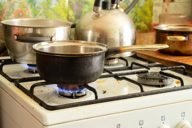 uma panela suja fica em um fogão a gás sujo na cozinha em casa, cozinhando sopa no fogão, fogão a gás - saucepan fire steam soup - fotografias e filmes do acervo