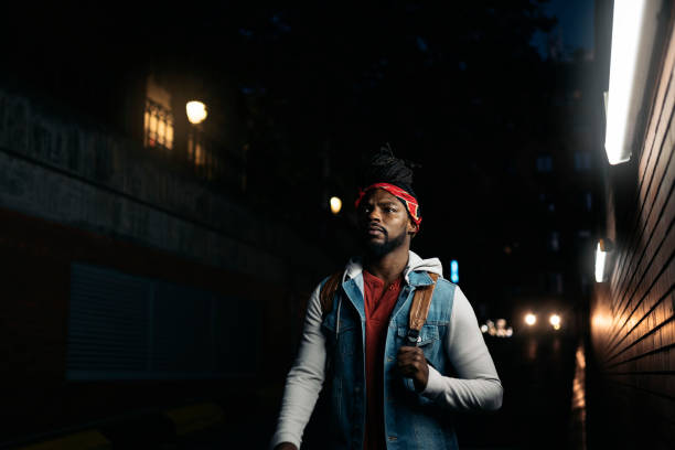 Stock photo of serious african american boy with dreadlocks walking in the street at night.