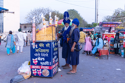 Anandpur Sahib, Punjab, India - March 2022: An indian seller selling the souvenir and food item on the streets of anandpur sahib during the hola mohalla festival.