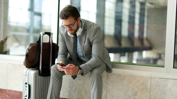 istock Businessman using phone while waiting for a train at train station 1398838025