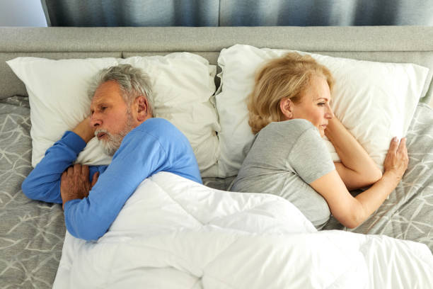 Upset senior couple ignoring each other in bedroom stock photo