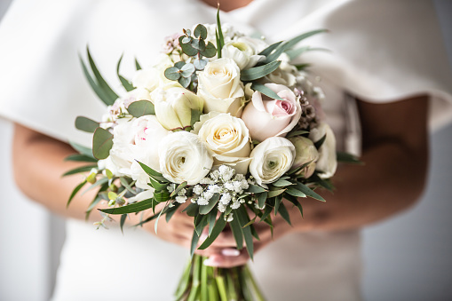 Detail of bride holding white wedding flowers bouquette in her hands.