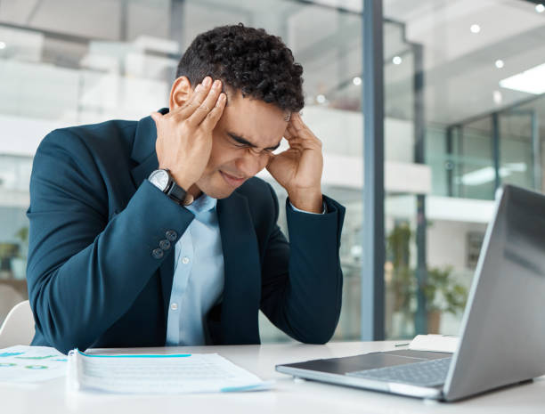istock Young angry mixed race businessman suffering from a headache while upset and working on a laptop at work. One hispanic businessperson looking stressed working at a desk in an office 1398840968
