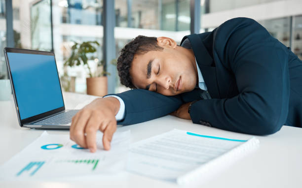 istock Young mixed race businessman resting and working on a laptop at a table alone at work. One stressed hispanic businessperson sleeping while working at a desk in an office 1398841088