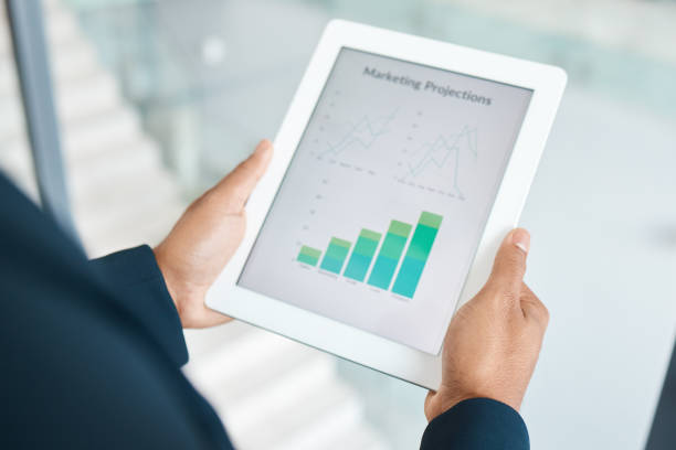 istock Businessperson standing looking at data and stats holding and using a digital tablet while standing at work. Businessman doing research working on a digital tablet alone in an office 1398841218