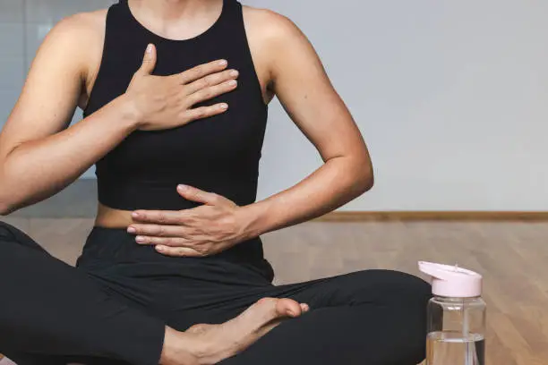 Photo of Woman doing breathing exercise sitting in lotus position.