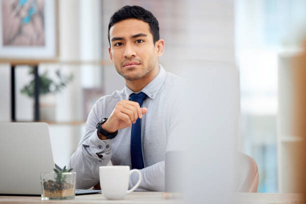 istock Young serious mixed race businessman working on a laptop alone in an office at work. One focused hispanic businessperson sitting at a desk at work 1398844372