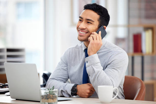istock Young happy mixed race businessman on a call using a phone and  sitting in an office at work. One hispanic male businessperson talking on the phone while thinking at work 1398844387