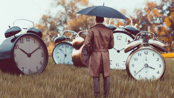 istock Surreal scene with man watching big alarm clocks on a field 1398845147