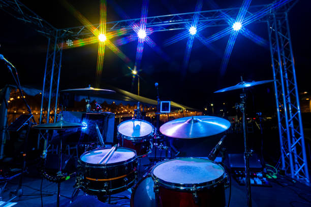 Full Drum Set Kit at Live Outdoor Music Show at Night with Microphone and Yellow Cool Blue Lights Nightlife. Full Drum Set Kit at Live Outdoor Music Show at Night with Microphone and Yellow Cool Blue Lights Nightlife. snare drum stock pictures, royalty-free photos & images