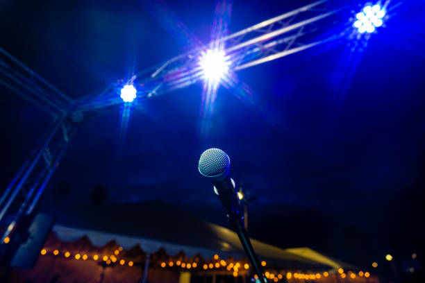 commedia o spettacolo di musica dal vivo di notte all'aperto con microfono e luci blu vita notturna - asta del microfono foto e immagini stock