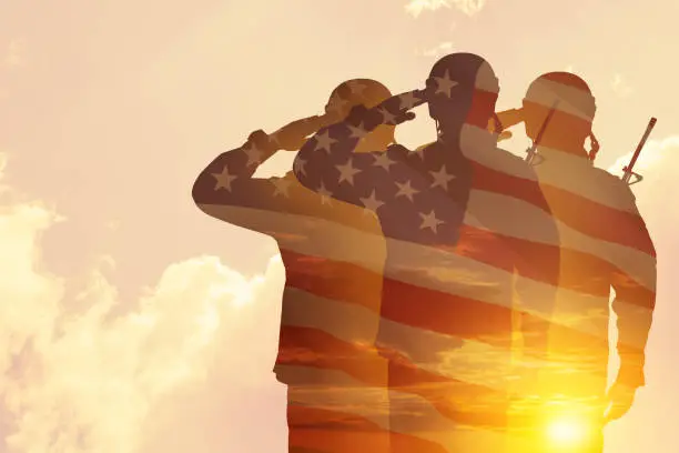 Photo of Silhouettes of soldiers with print of sunset. Greeting card for Veterans Day, Memorial Day, Independence Day.