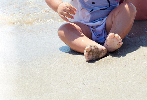 Baby feet on the beach. Sand. Rest by the sea with children.