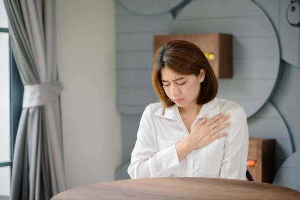 An Asian woman clutched her chest due to suffering from a sudden heart attack. stock photo