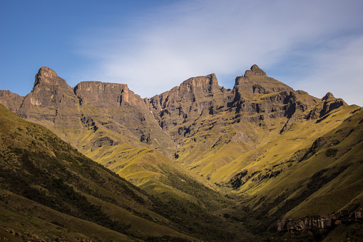 The tall craggy cliffs in the Injisuti region of the Drakensberg Mountains on a clear sunny day. These iconic cliffs and peaks of the Drakensberg Mountains formed due to the combination of the Jurassic period large flood basalt during the break-up of the Gondwana Supercontinent and erosion from the later uplift of the African Continent. The Drakensberg Park were declared a Unesco World Heritage site in 2000 to protect the natural habitats, but also due to its cultural significant since it has the largest concentration of rock paintings in Sub Sahara Africa.