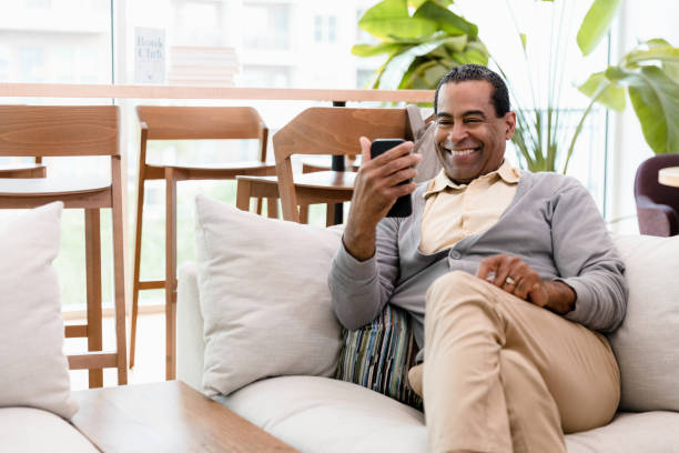 istock Mature man sitting on sofa smiles for selfie 1398854634