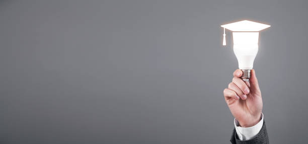 istock Male hand showing light bulb with a graduation cap symbol. Education 1398856132