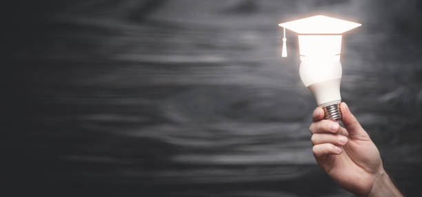 istock Male hand showing light bulb with a graduation cap symbol. Education 1398856136
