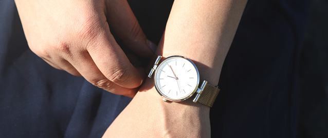 Caucasian girl with a wristwatch in hand.
