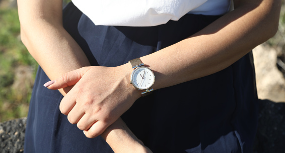 Caucasian girl with a wristwatch in hand.