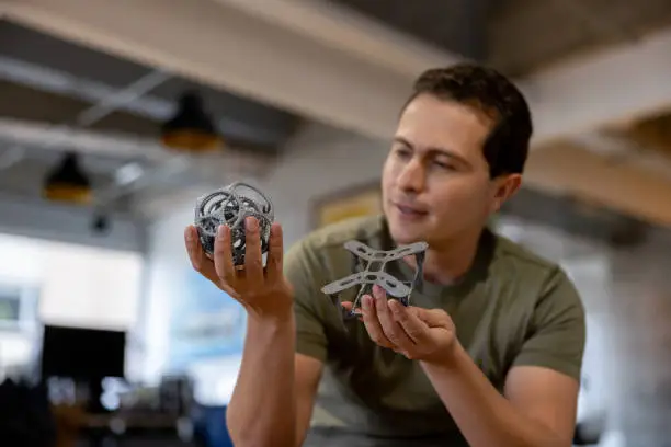 Creative man holding two 3D printed objects at his office - innovation technology concepts