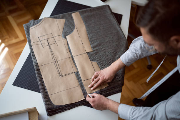 istock High angle view of male tailor outline with chalk, pattern on the textile 1398863090