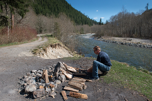 Adult man chopping wood to build a campfire at a dispersed campsite along the Skagit river, British Columbia, Canada