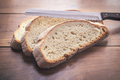 Three bread slices and a knife over a wood table