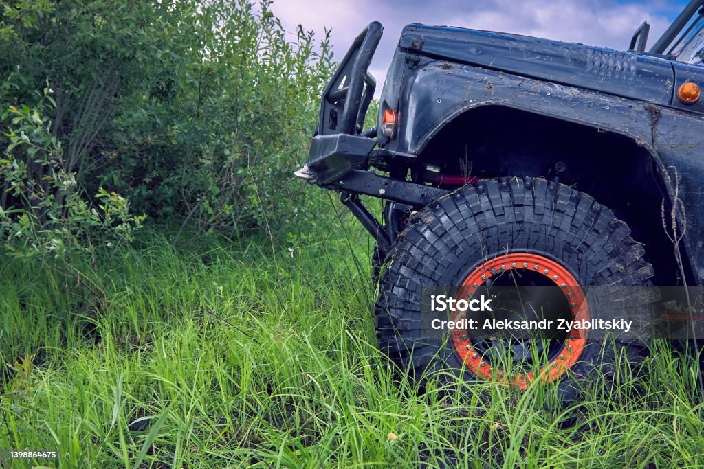 4x4 off-road car overcomes an obstacle going up the hill 4x4 off-road car overcomes an obstacle while climbing uphill. Toothy tires to overcome extreme obstacles. Off-Road Vehicle Stock Photo