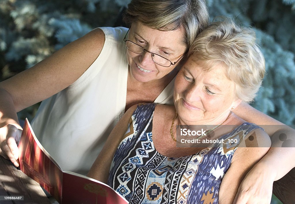 Reading together Two women reading a book together.  Active Lifestyle Stock Photo