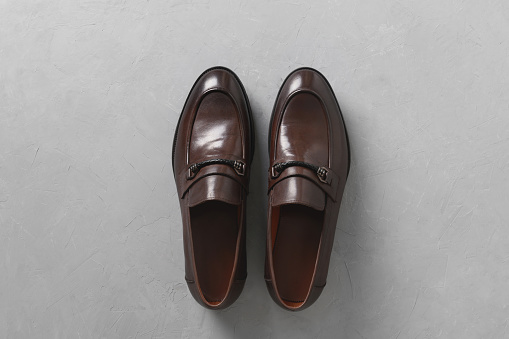 Classic male brown leather shoes isolated on gray concrete background. Top view. Flat lay.