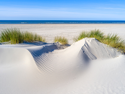 Summer in England. Creative photograph of sand dunes against a blue sky with clouds. Camber Sands, East Sussex along English Channel.