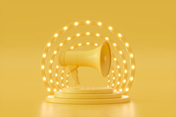 istock Megaphone on podium with glowing spot lights yellow background 1398867141