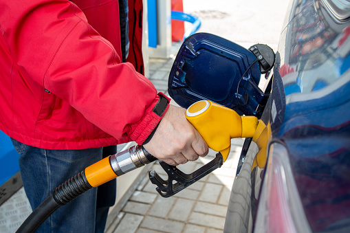 A man pours gasoline into the gas tank of a car at a gas station. Fuel for cars, transport.