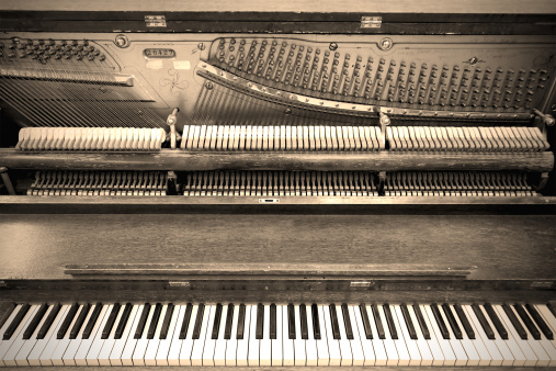 Old sepia photo of an old fashioned piano, opened up.