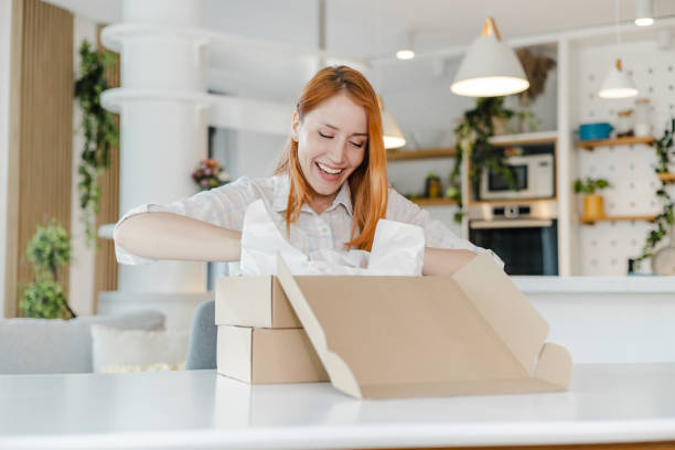 Young woman opens ordered items from the cardboard box stock photo